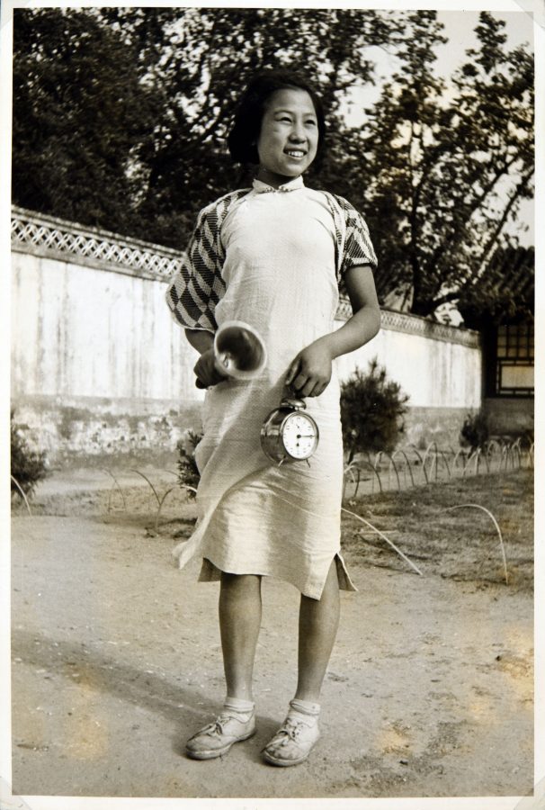 Student at the Peking Jiyu Gakuen School rings a bell and holds a clock.