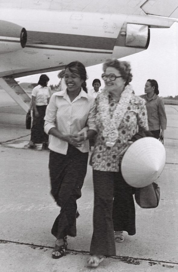 Two women walking across the tarmac at an airport