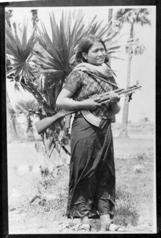 Full-length portrait of a female soldier with a gun slung over her shoulder