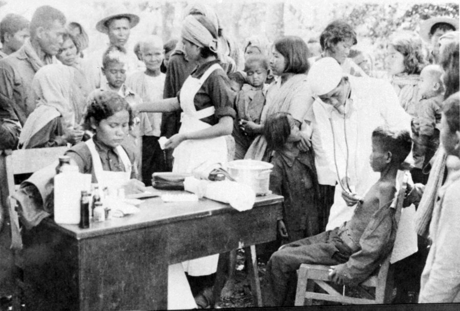 medical team treating children at an outdoor table.
