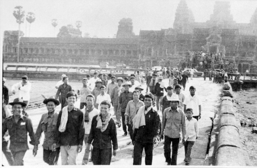 Smiling crowd of people walking away from a temple