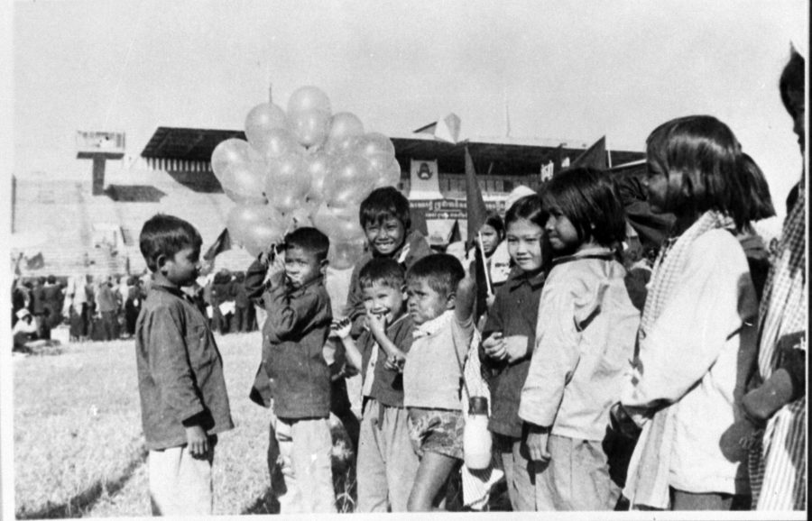 A group of children some holding balloons, at a stadium